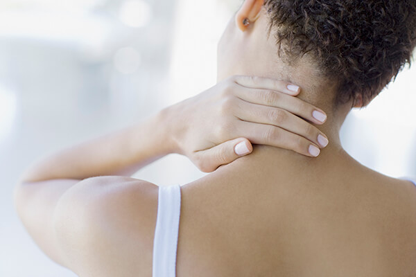 Woman grabbing the back of her neck in pain