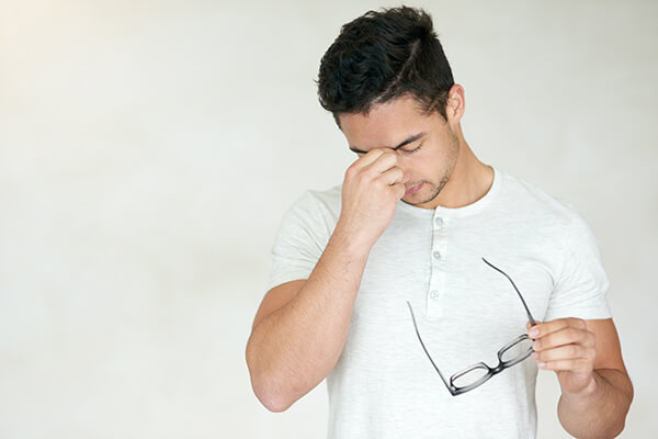 Man squeezing in between his eyes due to eye pain